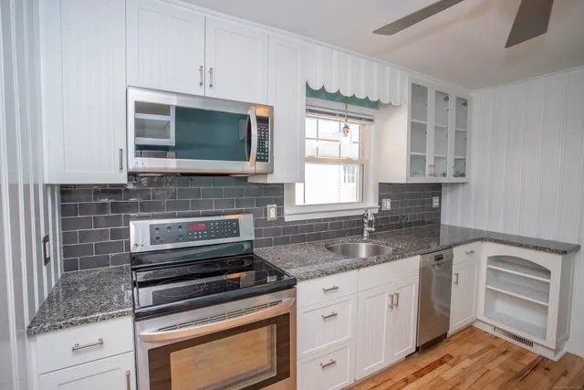 a kitchen with granite countertop a stove sink and microwave