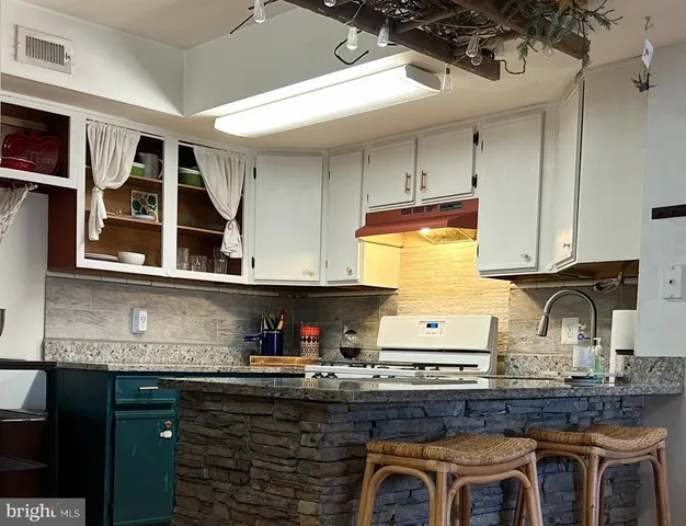 a kitchen with granite countertop a stove a sink and cabinets