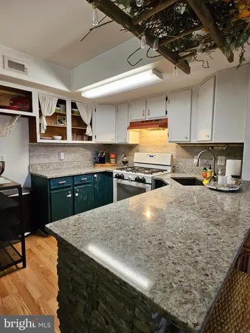 a kitchen with stainless steel appliances granite countertop a sink a stove and a cabinets