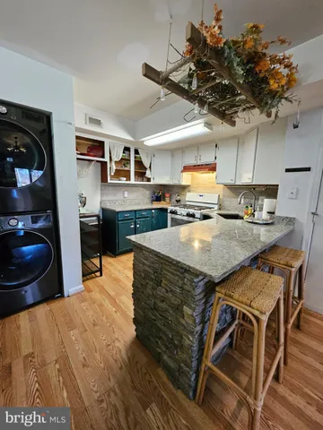 a kitchen with stainless steel appliances granite countertop a table chairs in it and wooden floors
