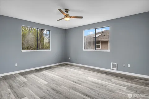a view of an empty room with a window and wooden floor