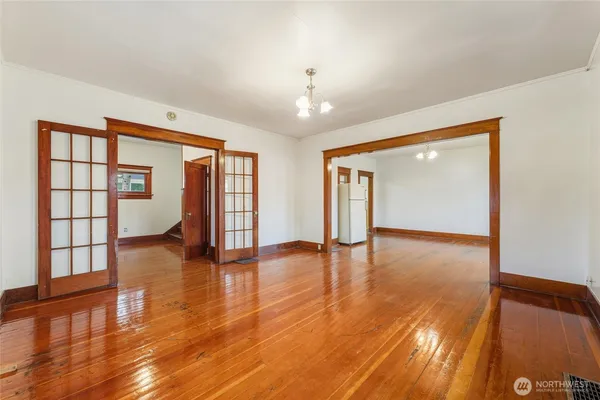a view of an empty room with window and wooden floor
