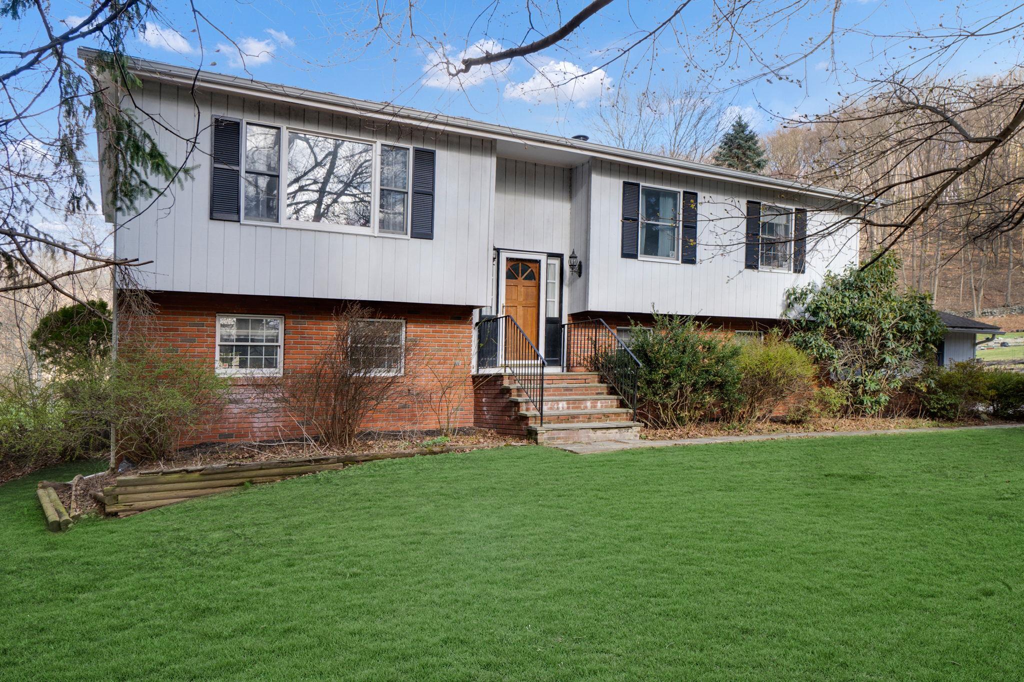 Raised ranch featuring a front lawn and brick siding