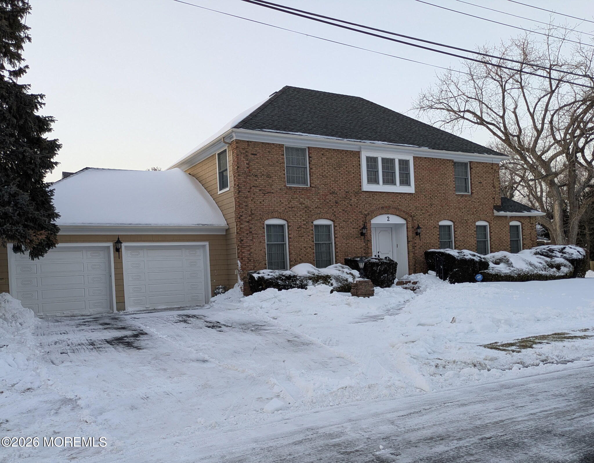 a front view of a house with a yard covered in snow