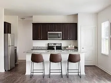 a kitchen with stainless steel appliances granite countertop a stove a refrigerator a microwave a dining table and chairs