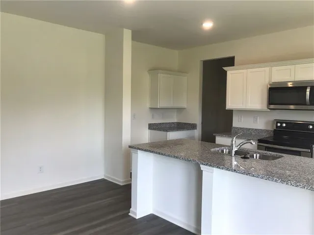 a kitchen with granite countertop a sink and a stove top oven