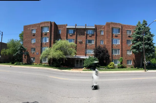 a front view of multi story residential apartment building with yard and traffic signal