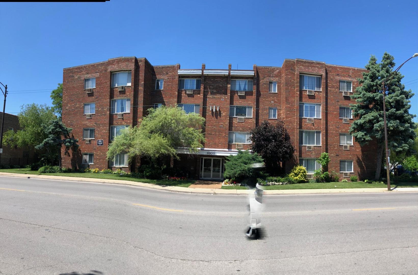 a front view of multi story residential apartment building with yard and traffic signal
