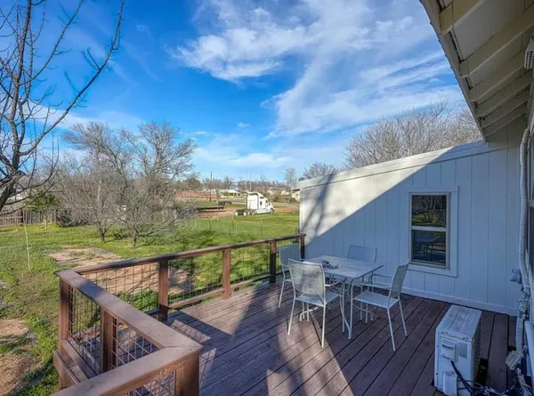 a view of a roof deck with table and chairs a barbeque with wooden floor and fence