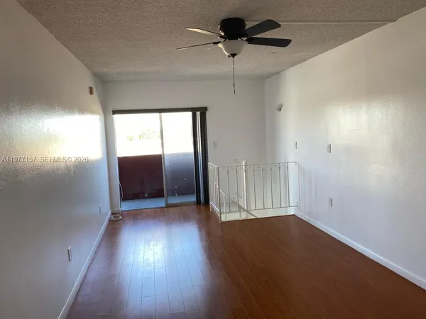 an empty room with wooden floor chandelier and windows