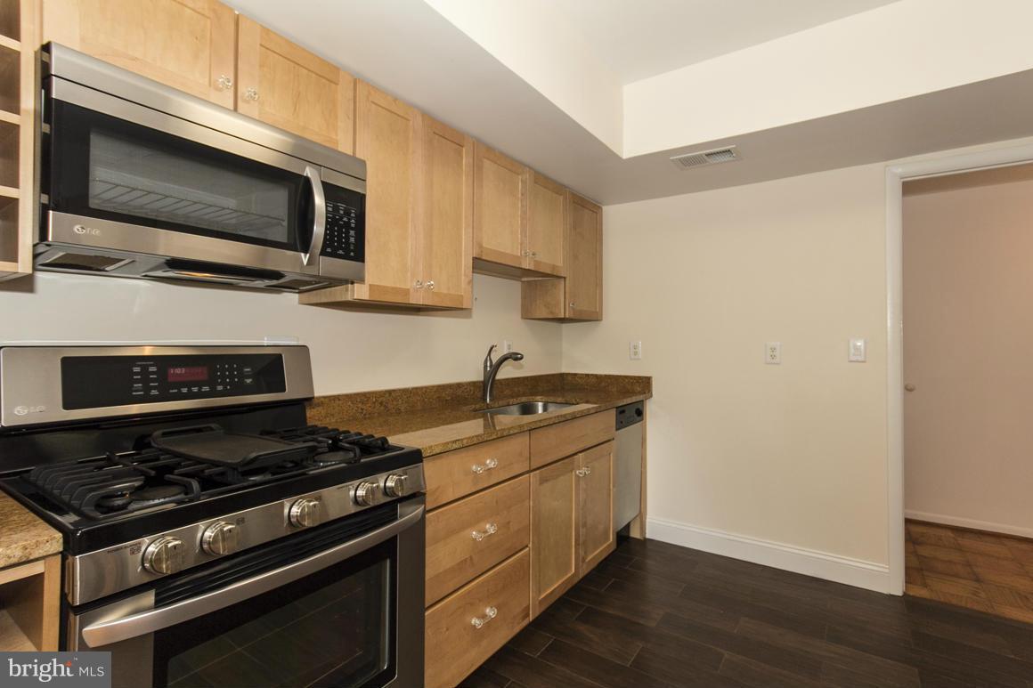 121 Cross Keys Road, Unit A Baltimore, MD 21210 - Photo 4 of 24 a kitchen with stainless steel appliances wooden cabinets and a stove top oven