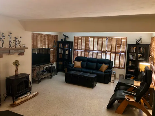 a living room with furniture a flat screen tv and floor to ceiling window