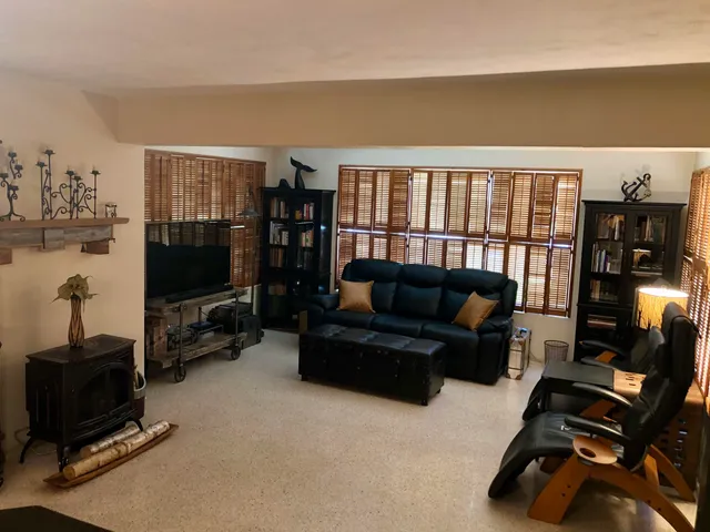 a living room with furniture a flat screen tv and floor to ceiling window