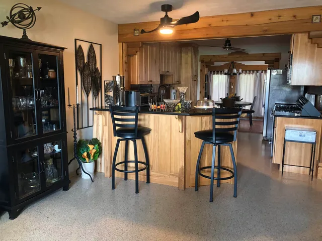 a kitchen with stainless steel appliances kitchen island granite countertop dining table chairs and a refrigerator