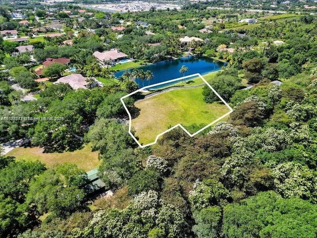 an aerial view of a residential houses with outdoor space and trees