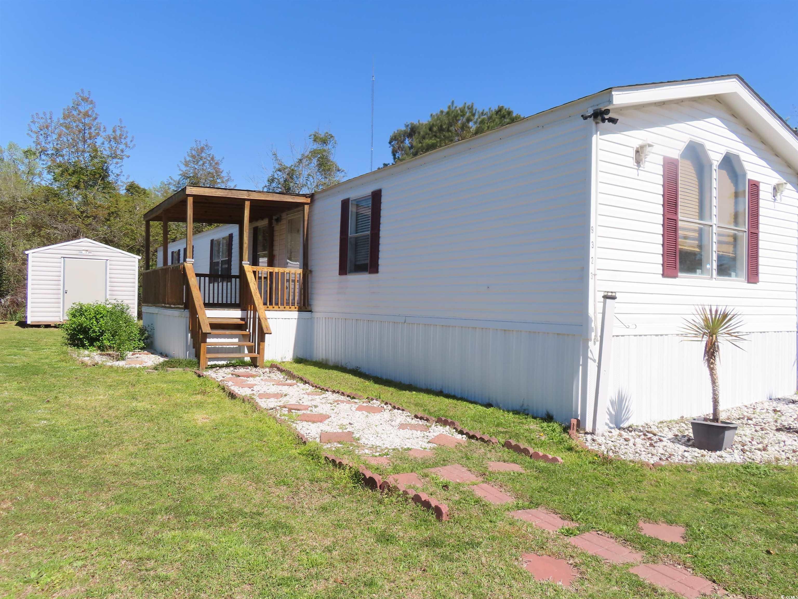 View of front of property with an outdoor structure, a shed, and a front lawn