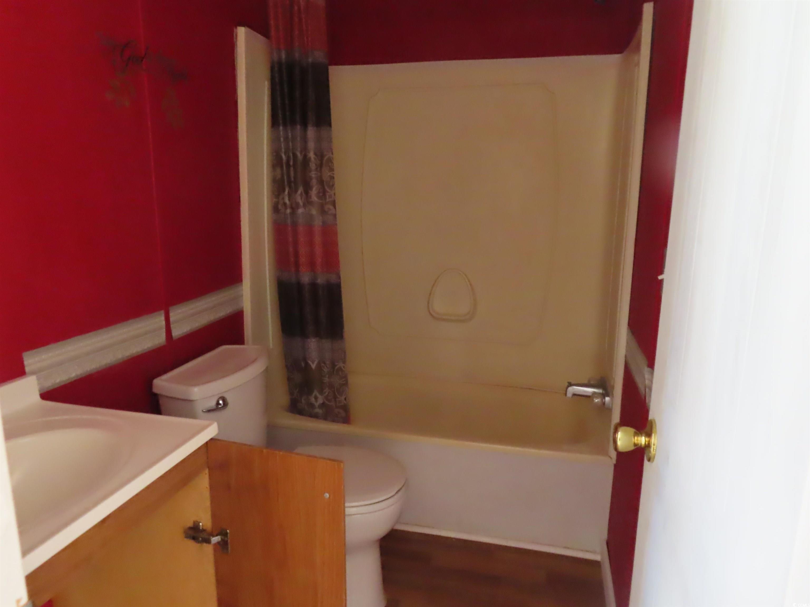 9323 Shoveler Drive Murrells Inlet, SC 29576 - Photo 16 of 23 Bathroom featuring toilet, wood finished floors, vanity, and shower / bath combo with shower curtain
