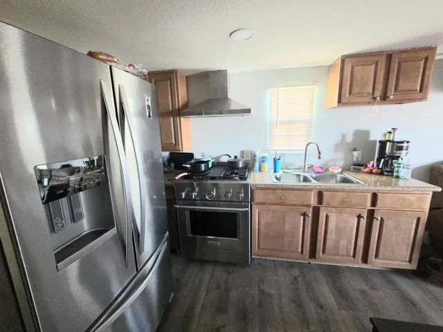 a kitchen with stainless steel appliances a refrigerator sink and wooden floor