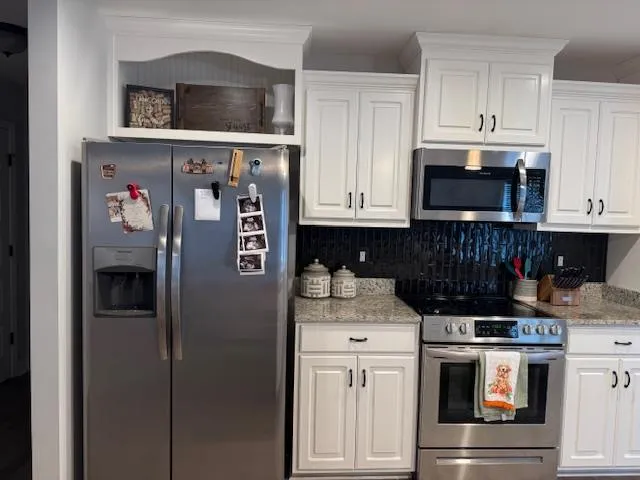 a kitchen with stainless steel appliances granite countertop a refrigerator and a stove top oven