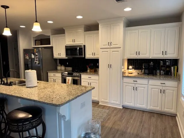 a kitchen with kitchen island granite countertop a sink a center island and stainless steel appliances