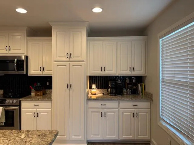 a kitchen with white cabinets and appliances