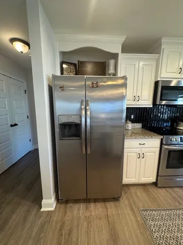 a kitchen with stainless steel appliances granite countertop a refrigerator a stove and a wooden floors