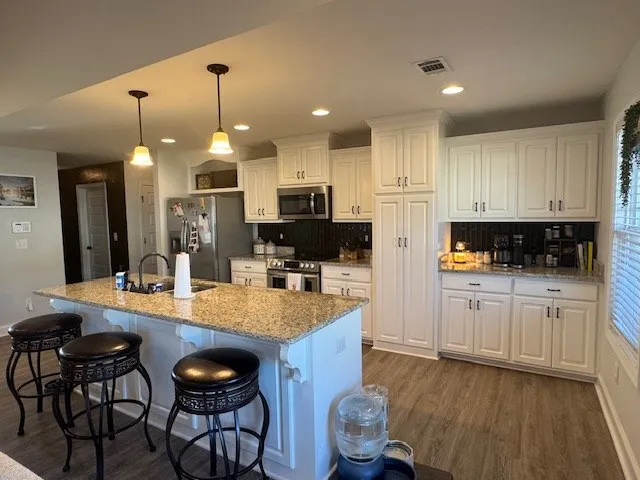 a kitchen with kitchen island granite countertop a sink a center island and cabinets