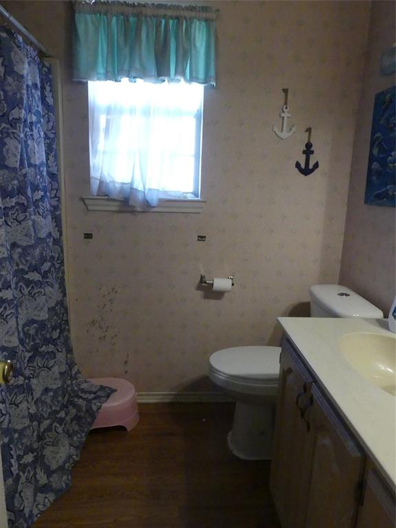 606 West Mulberry Street Decatur, TX 76234 - Photo 12 of 20 Bathroom with a shower with shower curtain, wallpapered walls, toilet, wood finished floors, and vanity