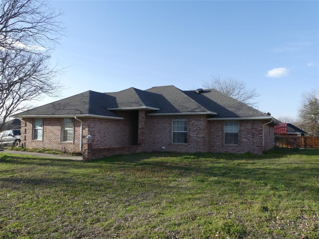 606 West Mulberry Street Decatur, TX 76234 - Photo 4 of 20 View of property exterior featuring a yard, brick siding, and roof with shingles