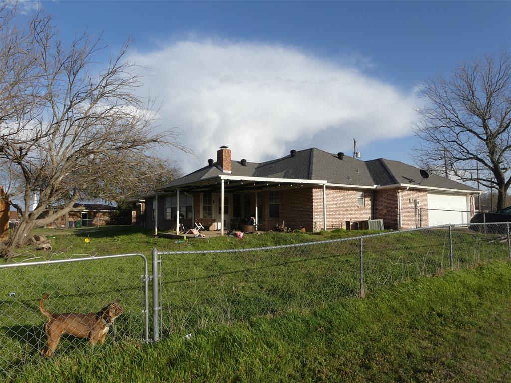 606 West Mulberry Street Decatur, TX 76234 - Photo 7 of 20 Back of house featuring a lawn, a fenced backyard, an attached garage, brick siding, and a chimney