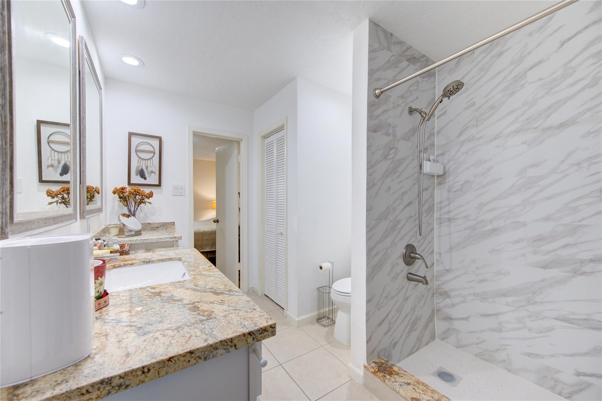 1901 South Voss Road, Unit 4 Houston, TX 77057 - Photo 17 of 26 a bathroom with a granite countertop sink a toilet and shower