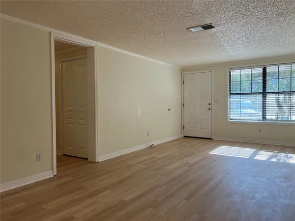 a view of an empty room with wooden floor and closet
