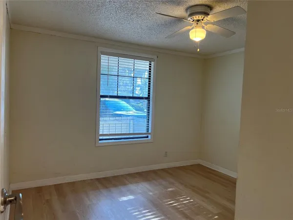 an empty room with wooden floor and fan