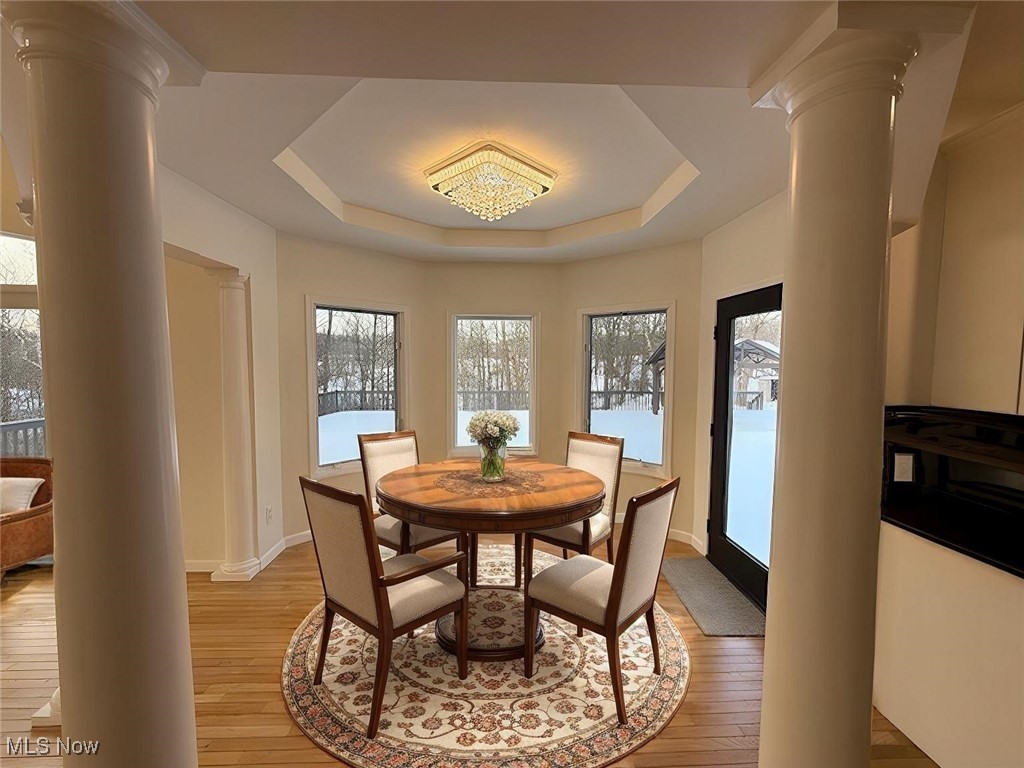 31295 Arthur Road Solon, OH 44139 - Photo 24 of 50 Dining room featuring a tray ceiling, decorative columns, and light wood-type flooring