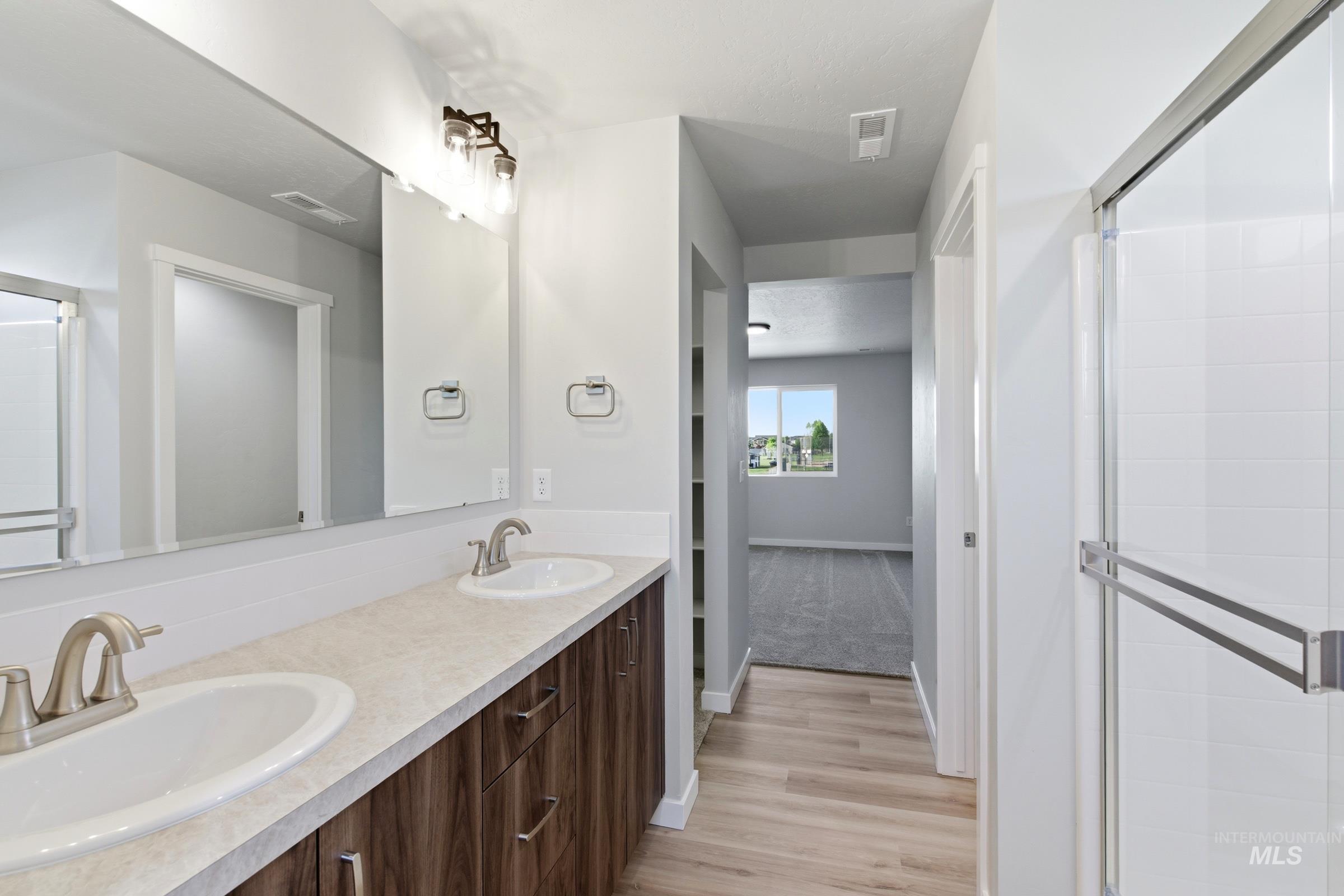 13709 Redway Court Caldwell, ID 83607 - Photo 22 of 28 Bathroom featuring a double vanity with undermount sinks, bronze finish hardware, and a framed mirror