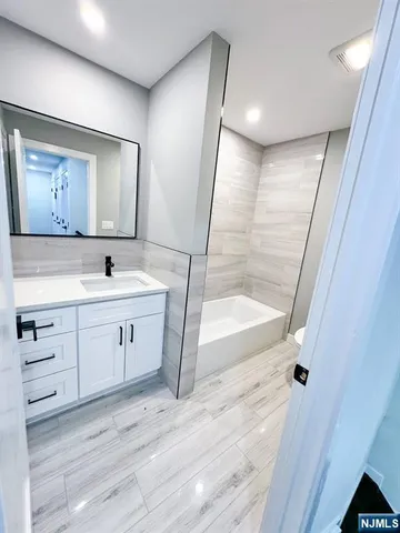 a spacious bathroom with a double vanity sink a mirror and a bathtub