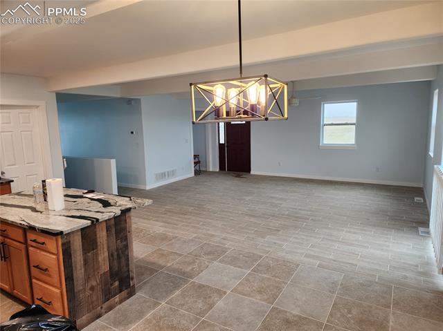 32174 Torrence Road Yoder, CO 80864 - Photo 13 of 13 Kitchen with baseboards, light stone countertops, open floor plan, and brown cabinetry
