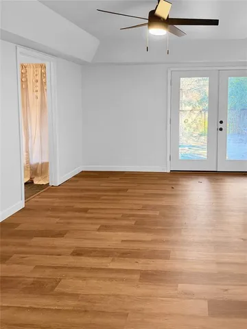 a view of an empty room with wooden floor and a window