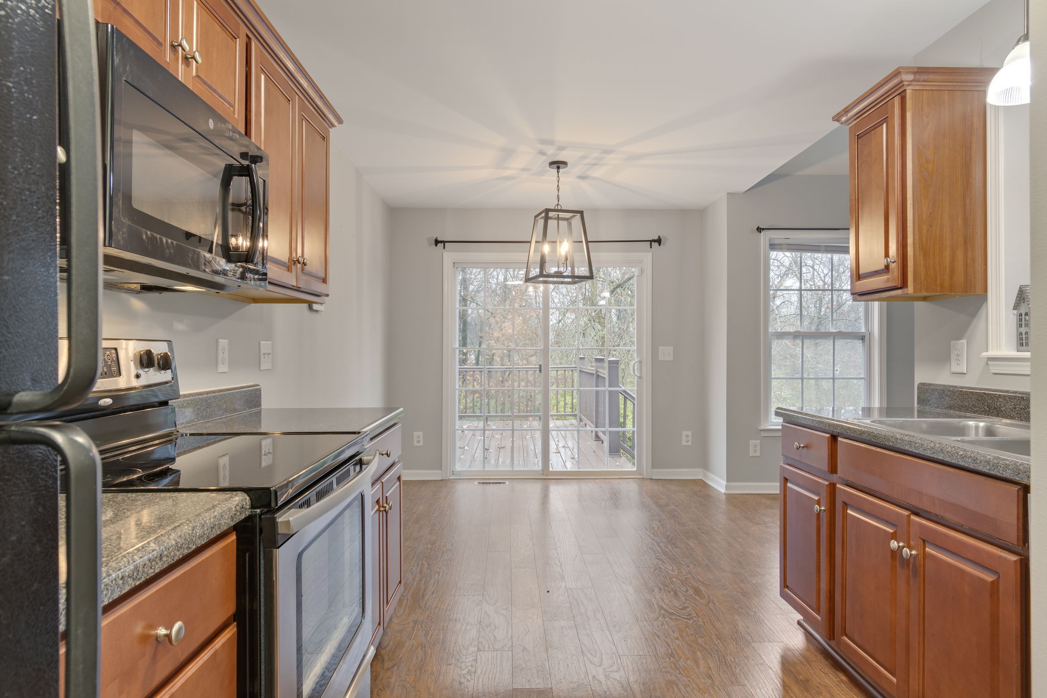 1112 Golf View Way Spring Hill, TN 37174 - Photo 22 of 47 a kitchen that has a sink a microwave oven a stove and white cabinets with wooden floor