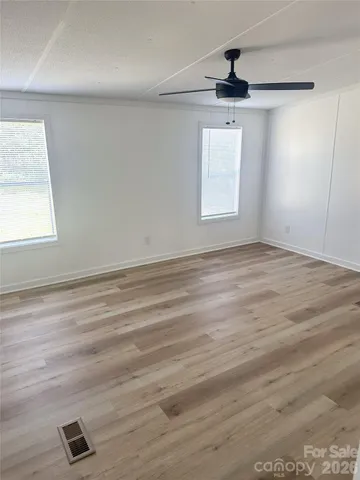 an empty room with wooden floor cabinet and windows