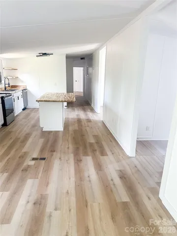 a view of a kitchen with kitchen island a sink wooden floor and living room view