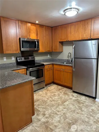 a kitchen with stainless steel appliances granite countertop a stove a sink dishwasher a refrigerator and a microwave
