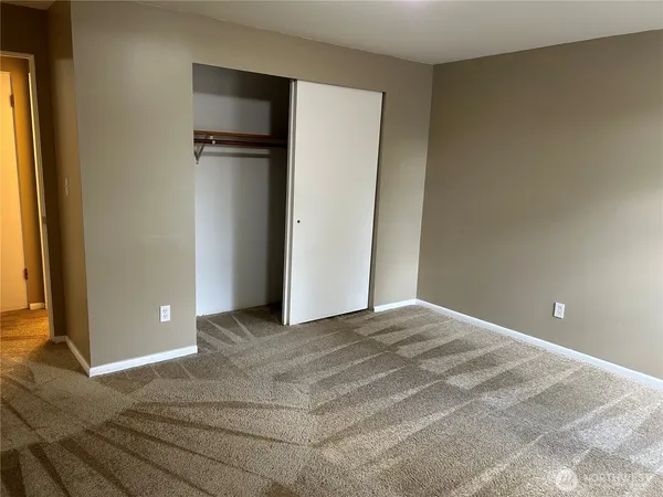 a view of an empty room with closet and a window