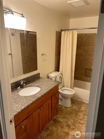 a bathroom with a granite countertop sink toilet and shower