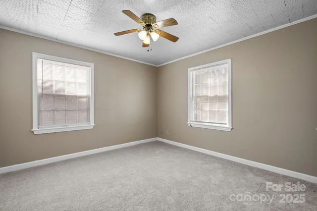 an empty room with windows and chandelier fan