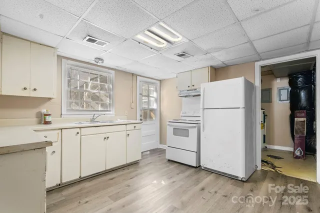 a kitchen with refrigerator a stove a sink dishwasher and white cabinets with wooden floor