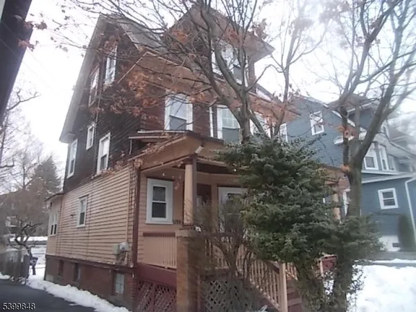 a front view of a house with a tree
