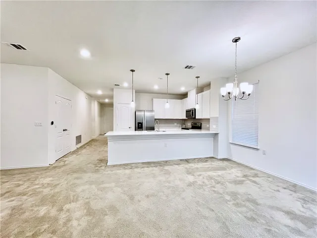 a large kitchen with kitchen island a sink stainless steel appliances and a chandelier