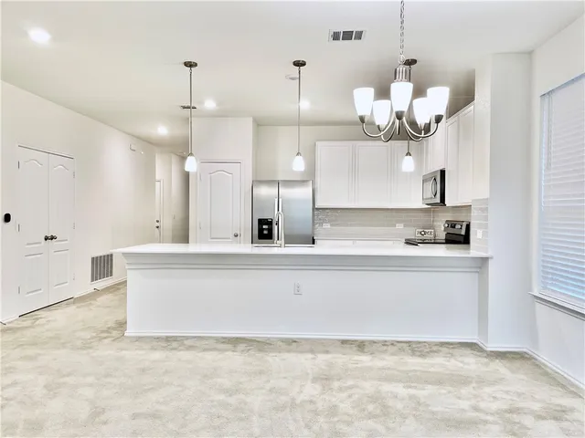 a large kitchen with cabinets a sink and a chandelier