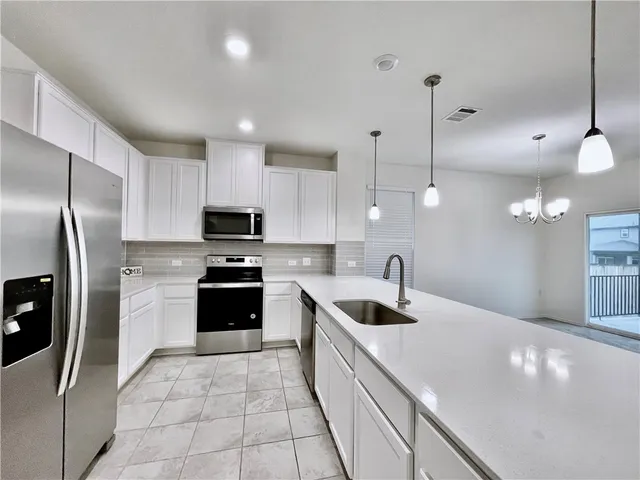 a kitchen with kitchen island granite countertop a sink a counter top space appliances and cabinets